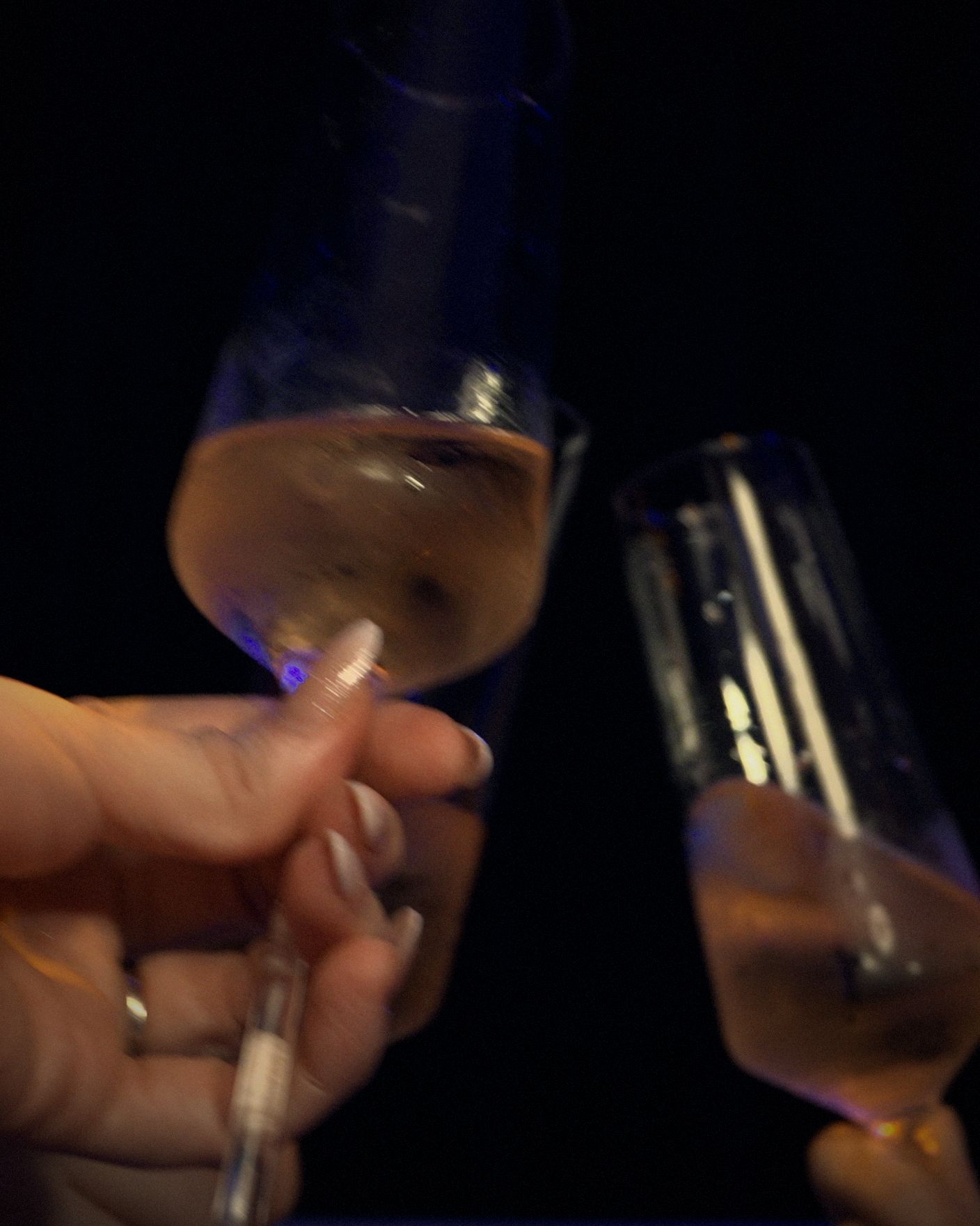 Two champagne flutes meeting in a toast in the dark