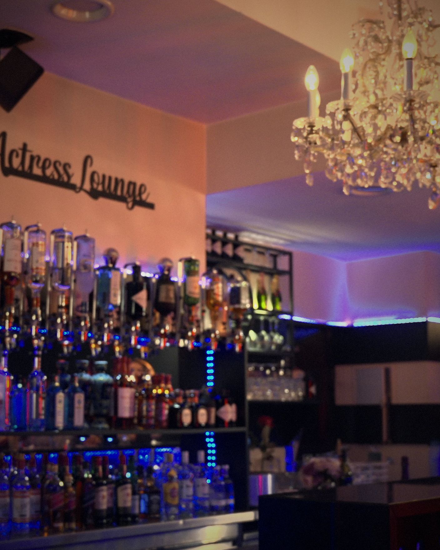 Crystal chandelier over the back bar, its bottles lit beneath the Actress Lounge sign