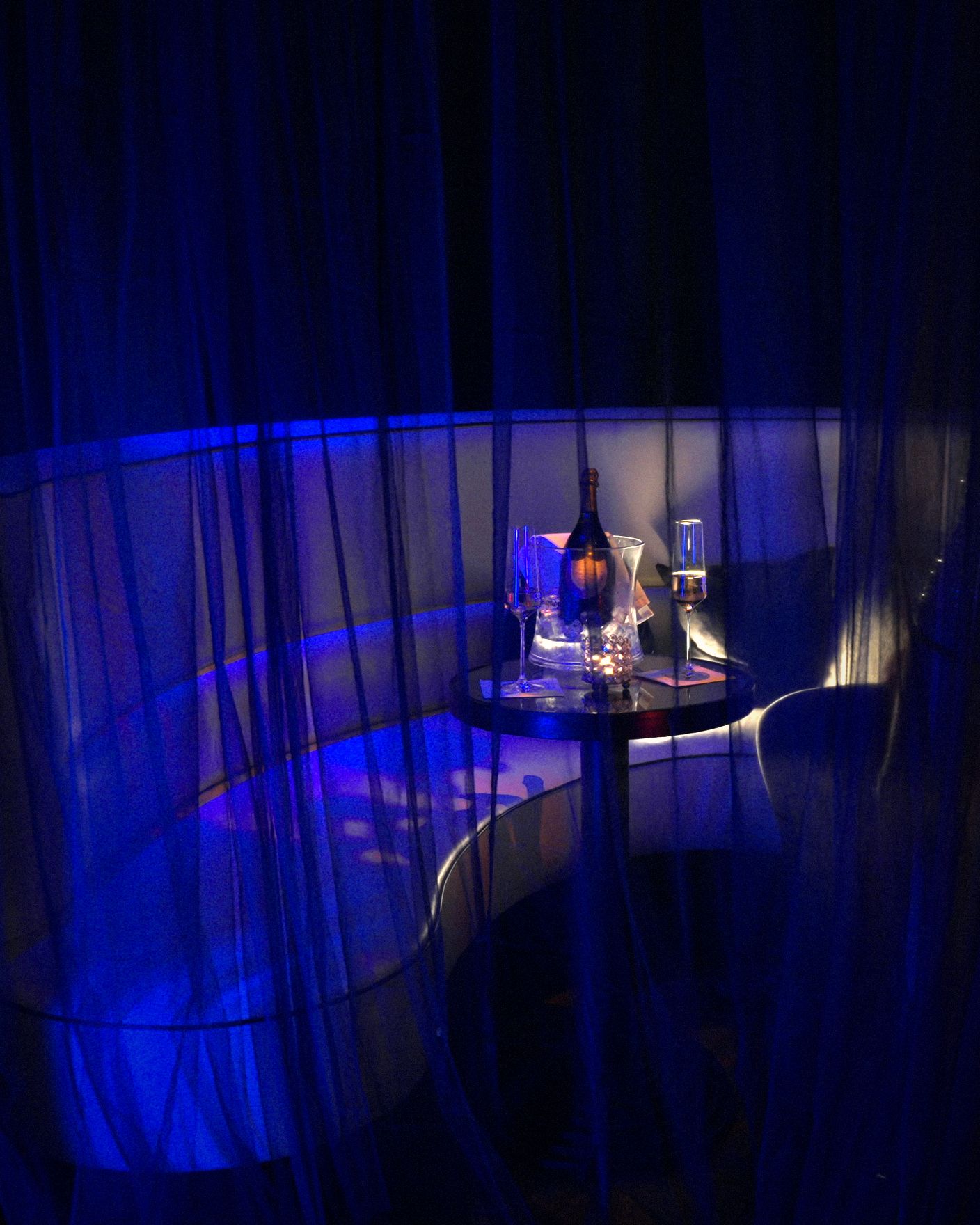 A private booth with champagne on the table, half hidden behind a sheer curtain