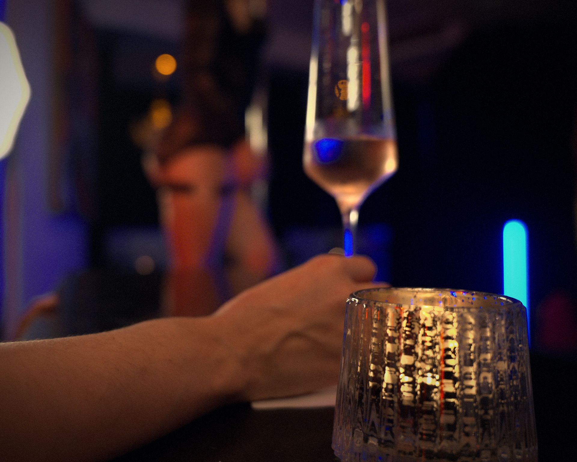 A glass of champagne in hand at the candlelit bar, a performance glowing out of focus behind
